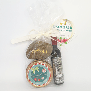 סט מתנה עטוף צלופן עם פותחן בצורת בקבוק, נר ריחני בקופסת פח ואבן עם ברכה בכיתוב זהב